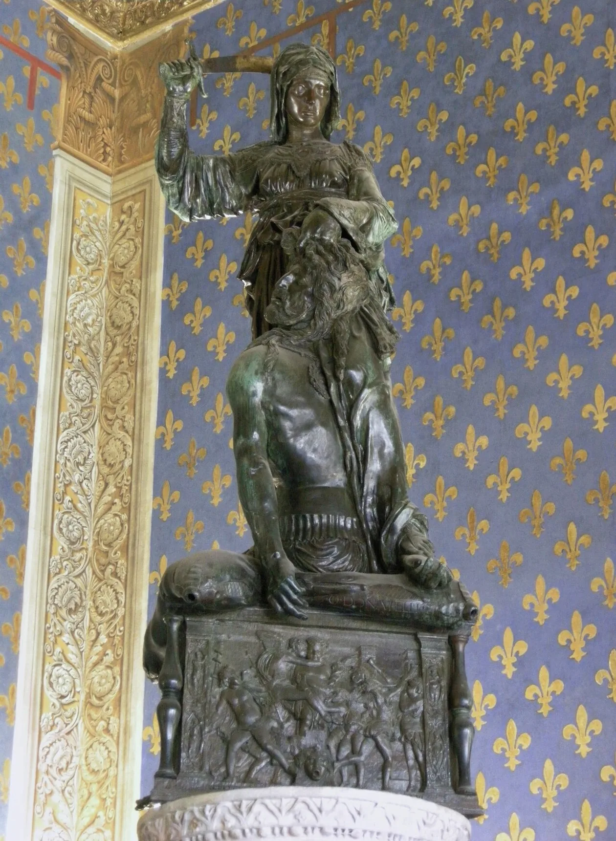 Donatello's bronze Judith and Holofernes against the fleur-de-lis walls of the Sala dei Gigli
