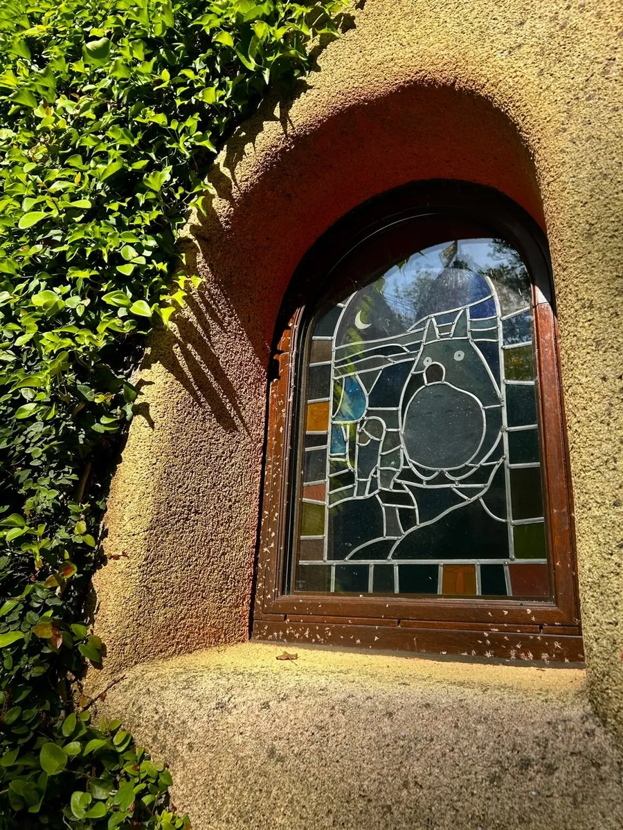 Ghibli Museum — arched stained-glass window of Totoro under a crescent moon