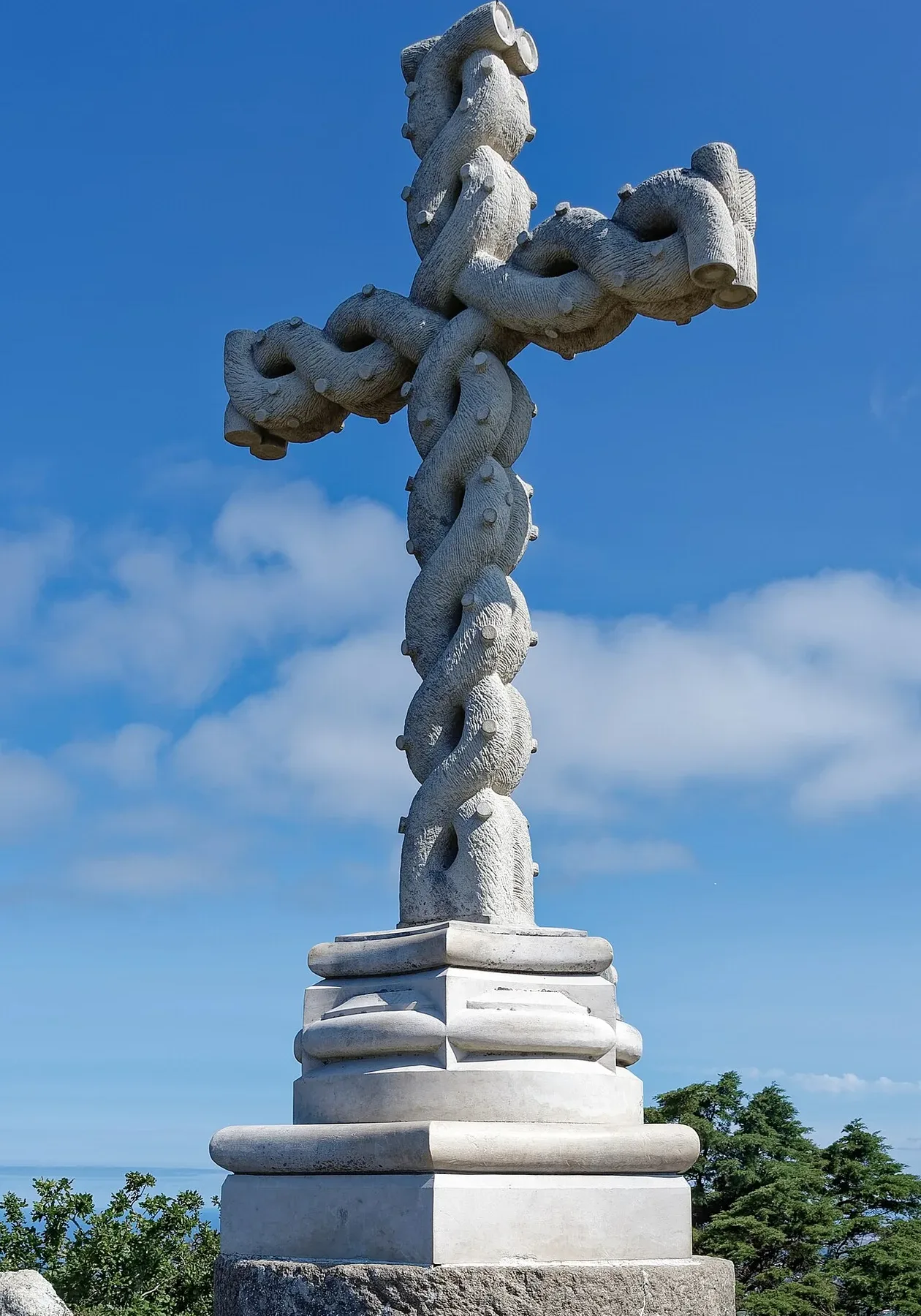 The braided stone High Cross on a granite outcrop at the summit of Pena Park, under a blue sky