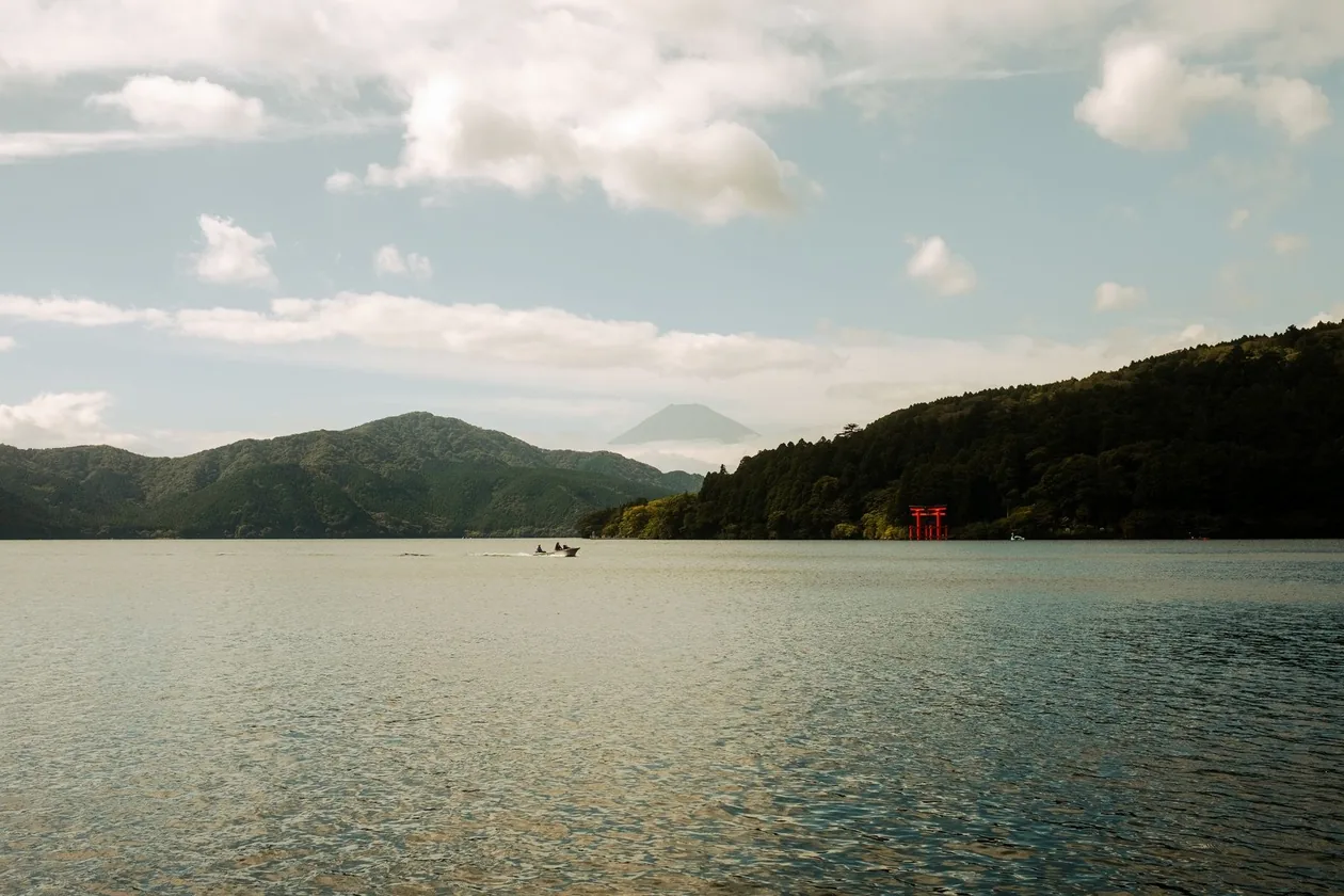Lake Ashi in Hakone with the red torii gate on the shore and Mount Fuji faint in the distance