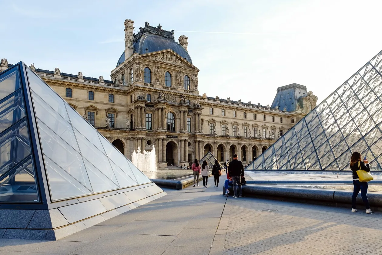 Louvre Museum glass pyramids and the Richelieu wing facade on a sunny day, Paris