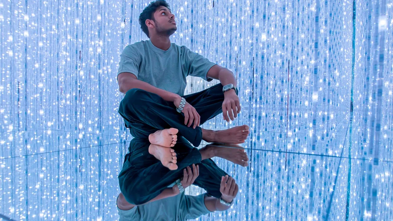 Barefoot visitor on a mirrored floor inside teamLab Planets Tokyo's light installation